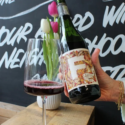 Forage red with a glass poured in West Didsbury Reserve in front of a blackboard with chalk writing.